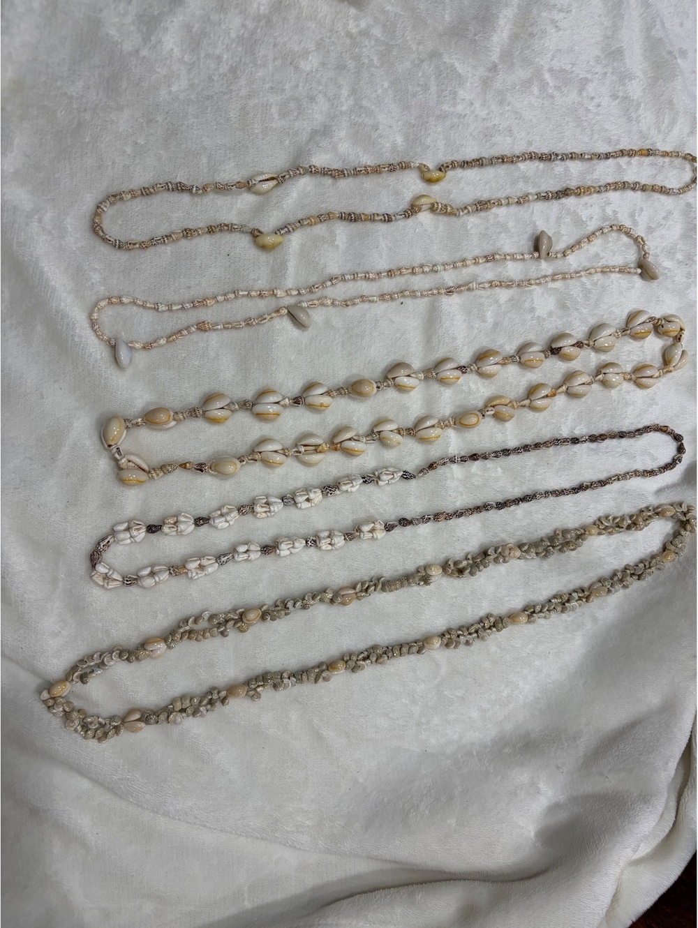 bundle of 4 seashell necklaces features various designs like cowrie puka shells